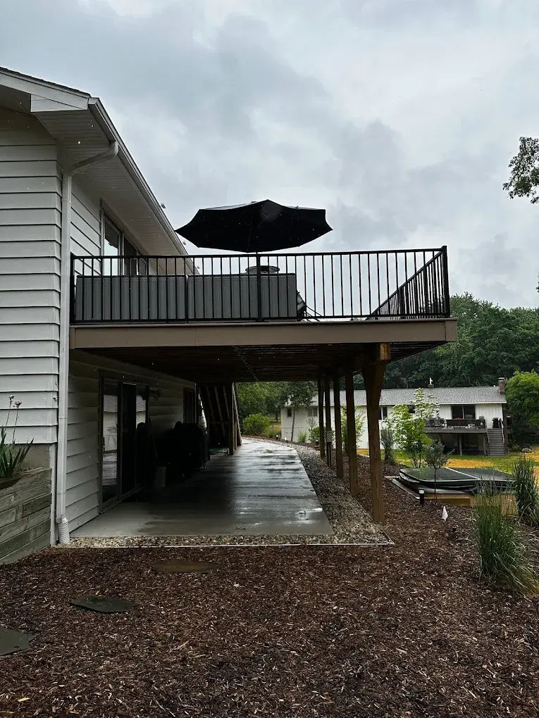 Elevated second-story deck with black metal railing and covered patio area below