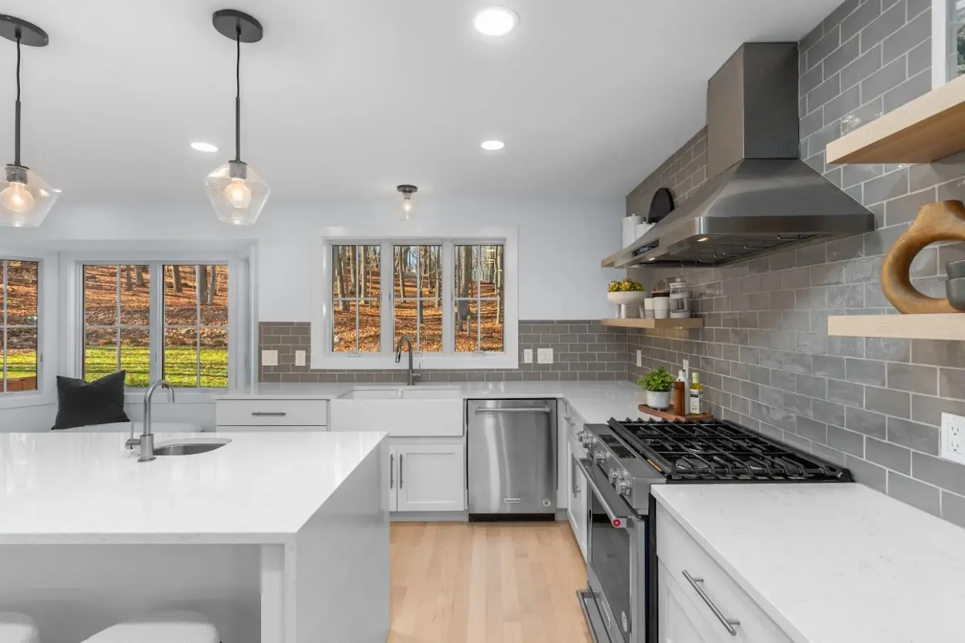 Remodeled kitchen with stainless steel range, gray tile backsplash, pendant lighting, and quartz countertop island