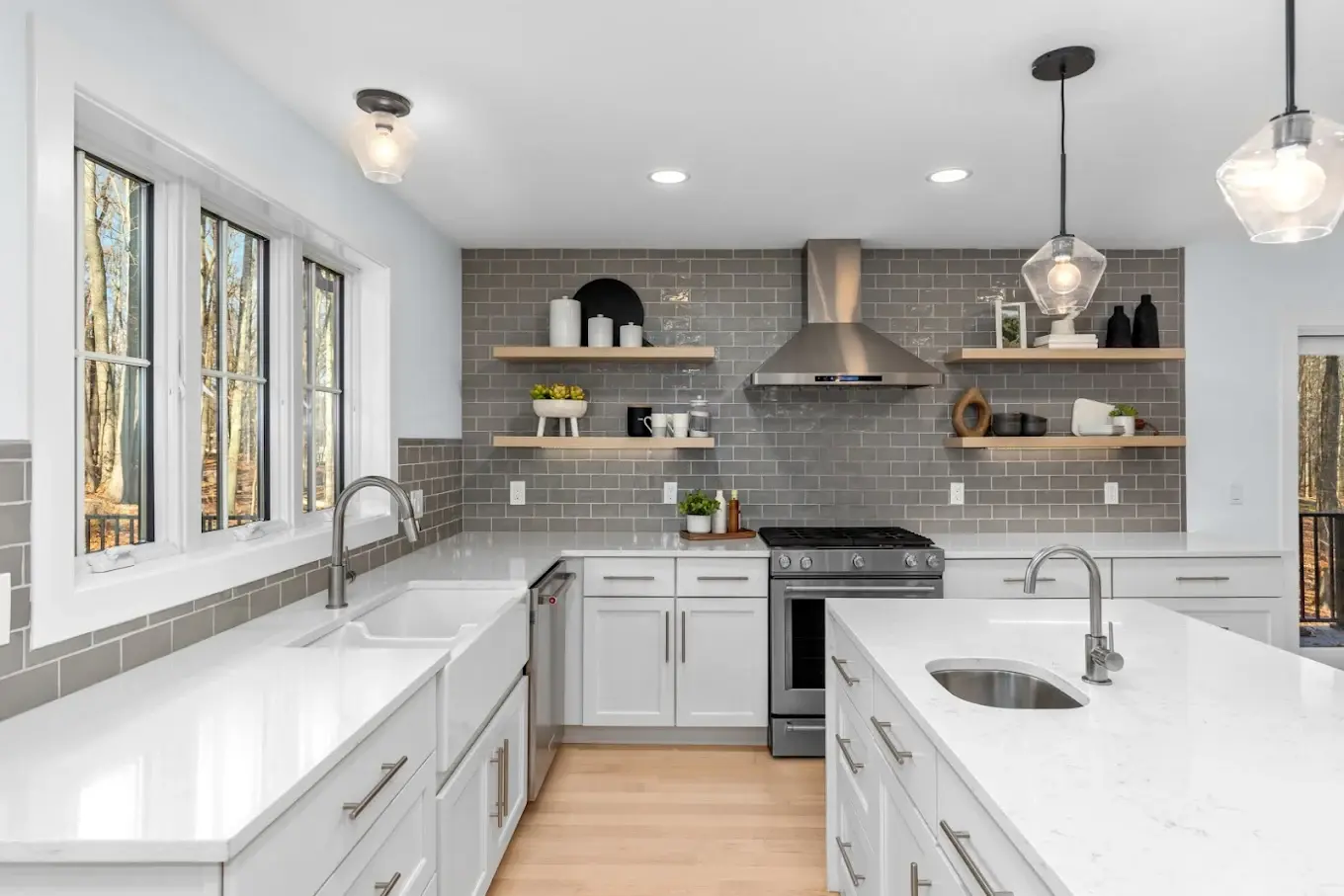 Completed kitchen remodel with white shaker cabinetry, quartz island, gray subway tile backsplash, and floating wood shelves